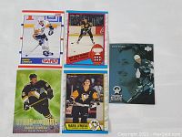 Five Mario Lemieux hockey cards displayed together on a white background, showing various designs and poses of Lemieux in his Penguins gear.