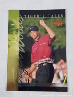 Front of 2001 Tiger Woods TT18 Tiger's Tales rookie insert card with image of Woods celebrating on golf course.