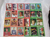 Photo showing assortment of 1973 O-Pee-Chee NHL hockey cards laid out on white surface.