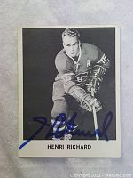 Front of black and white hockey card showing Henri Richard in Montreal Canadiens uniform with autograph in blue ink.