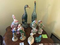 Full collection of ten ceramic bird figurines on a wooden table showing different bird styles and colors