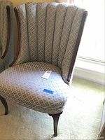 Chair photographed from an angle showing reupholstered blue patterned fabric upholstery, tufted channel back, and curved dark wood legs.