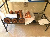Wooden bobbins, glass rolling pin and Christopher Radko ornament displayed on bottom shelf of a metal rack