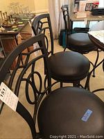 Three black metal bar stools shown at an angle, front view