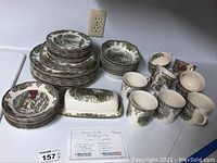 Full overview of all items in the set arranged on a counter showing various plates, bowls, cups, and a butter dish.