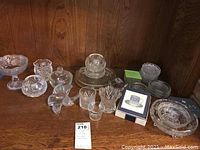 Full display of 12 crystal items including coasters, candy dishes, small bowls all with cut designs