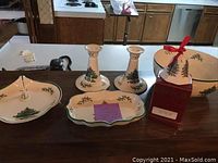 Full assortment of Spode Christmas tree servingware side by side on counter including divided dish, two candlesticks, bell, and covered bowl.