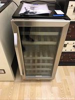 Front view of wine refrigerator showing glass door, stainless steel trim and shelves inside