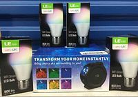 Four LE Ever lampUX WiFi Smart LED bulbs in open boxes with one starry light projector box shown.