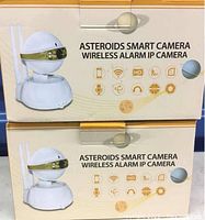 Two boxed Asteroids Smart Camera Wireless Alarm IP Cameras showing front of the boxes with product image and feature icons.