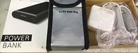 Black power bank, Li-Po safe bag, and Mac laptop charger in box.