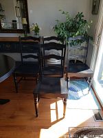 View of set of six dining chairs in dark wood with rattan-like seats, showing overall condition and style.