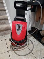 Front angled view of Husky power washer showing red and gray body with on/off switch and 1550 PSI text.