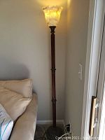 Full height view of the floor lamp showing the wooden stand and marble-like glass shade at top.