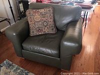 Front view of green leather Ethan Allen armchair with decorative pillow on seat, showing overall condition and style.