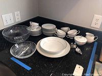 Full set of Mikasa B dining and serving ware arranged on counter showing dinnerplates, cups, creamer, sugar bowl, glass bowls, salt and pepper shakers