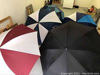 Five golf umbrellas arranged side by side showing the variety in panel colors and styles.