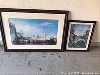 Two framed Venetian canal prints photographed against a wall, showing overall size and condition. Larger print on left and smaller on right.
