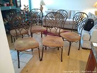 Front view of six wrought iron dining chairs arranged in living area showing cloth seats.