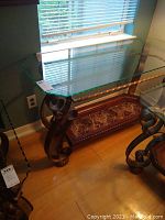 Full view of glass top with scalloped edge and wrought iron decorative leg