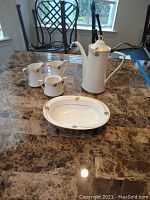 Photo showing entire set: coffee pot, two creamers, sugar bowl without top, casserole dish, salt shaker on a marble table.