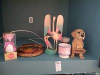 Photo of all items on shelf including bird figurine, resin dog welcome sign, wreath with candles, and boxed Hallmark gift