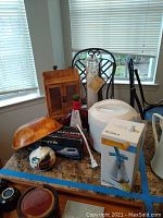 View of kitchen table with Aroma rice cooker, boxed Boska Table Grater Wind Mill, Toastmaster carving knife with wooden stand, Cucina salt grinder and other kitchen items