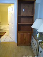 Front view of oak bookcase showing three shelves and lower cabinet with doors