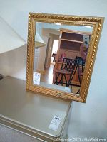 Front view of gold painted composite frame mirror showing rectangular reflective surface and decorative frame