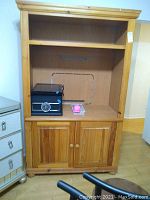 Front view of pine entertainment center showing upper shelf, central open compartment with cable management hole, and lower two-door cabinet storage.