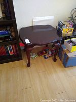 Full view of the mahogany side table showing top surface and table structure next to bookshelf and boxes.