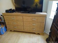Front view of composite wood dresser with six drawers, showing wood grain finish and metal handles
