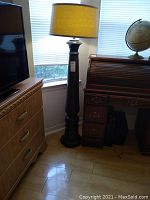 Full view of the ceramic floor lamp with burlap shade, positioned between furniture showcasing its height and style.