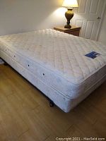 Full view of queen size bed setup with box spring on metal frame and mattress