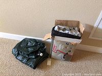 Two inflated or folded green Coleman air mattresses next to a partially opened box with one mattress partially packed inside.