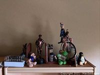 Overview photo of desk top figurines and toys on shelf, including golfer bookends, Uncle Sam bicycle, and plush animals.
