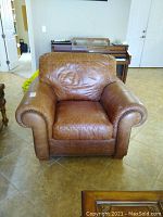 Front view of brown leather armchair showing rolled arms and cushioned seat and backrest.