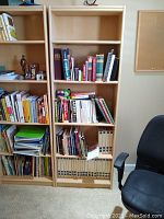 Full view of shelving unit placed next to another similar bookshelf, showing five shelves filled with various books and items (not included).