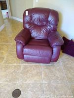 Full front view of burgundy leather rocker recliner chair showing padded armrests and cushioned back.