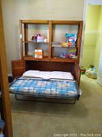 Front view of Murphy bed opened with mattress and shelves above holding toys and games.