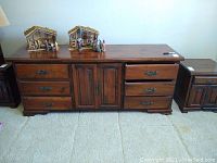 Full front view of the pine wood dresser showing six drawers and two-door cabinet in the center, sitting on carpeted floor with two small nativity scenes on top.