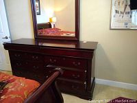 Front view of dark wood dresser with eight drawers underneath a large mirror, showing drawer handles and top surface