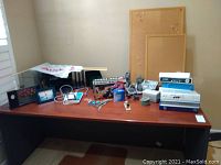 Wide shot of office desk with various office items including calculators, phones, binders, filing racks, and desk tools arranged on the tabletop