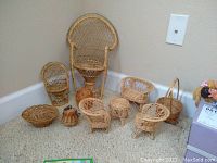 Wide shot of entire set showing all the small wicker doll furniture pieces arranged on floor against corner wall.