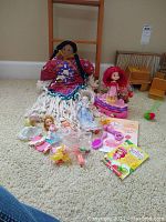 Overview of entire lot with Strawberry Shortcake doll, miniature porcelain dolls, cloth doll, and play accessories on beige carpet.