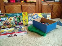 Photo showing LEGO Nexo Knights set box, Ultimate Operation Escape Room game box, KRE-O LEGO assortment, and Transformers set boxes arranged against wooden furniture.