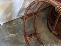 Close-up image of the curved rattan frame base showing joint connections and wear.