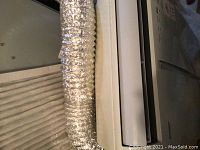 Close-up of aluminum flexible exhaust hose attached to the portable air conditioner