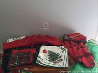 Photo showing stacks of folded Christmas-themed cloth napkins and vintage aprons on a wooden surface.