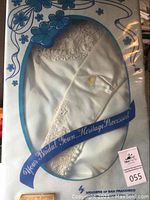 Wedding dress preserved inside original clear top presentation box showing lace detailing and fabric texture.